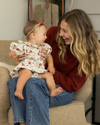 Rylee & Cru Lula Romper - Holiday Floral
Woman sitting on a couch holding a baby, both smiling