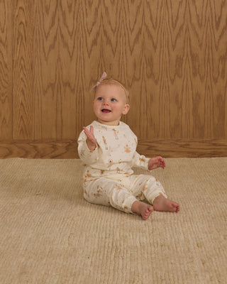 Rylee & Cru Henley Jumpsuit - Nutcracker
Baby sitting on a beige carpet with a wooden wall background