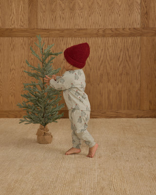 Rylee & Cru Long Sleeve Tee + Pant Set - Trees
Child in pajamas and red hat standing next to a small Christmas tree indoors.