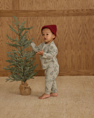 Rylee & Cru Long Sleeve Tee + Pant Set - Trees
Child in a red hat standing next to a small Christmas tree indoors.