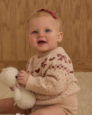 Rylee & Cru Fairisle Sweater - Bows
Baby wearing a patterned sweater holding a teddy bear against a wooden background