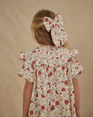Rylee & Cru Oversized Bow - Holiday Floral
Child wearing a floral dress with ruffled sleeves against a beige background