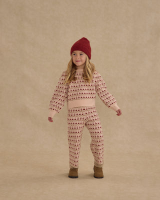 Rylee & Cru Jacquard Knit Set - Ruby Hearts
Child wearing a patterned outfit and red hat on a beige background