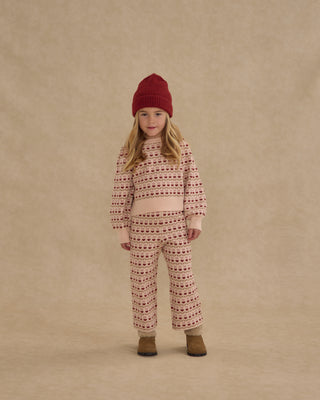 Rylee & Cru Jacquard Knit Set - Ruby Hearts
Child wearing a patterned outfit and red hat on a beige background