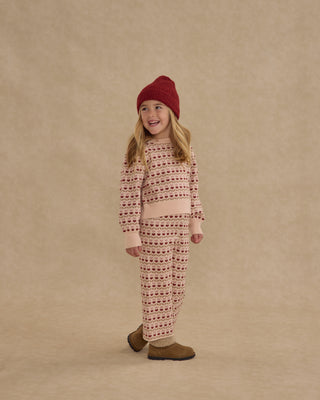 Rylee & Cru Jacquard Knit Set - Ruby Hearts
Child wearing a patterned outfit with a red hat on a beige background