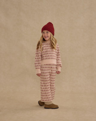 Rylee & Cru Jacquard Knit Set - Ruby Hearts
Child wearing a patterned outfit and red hat on a beige background
