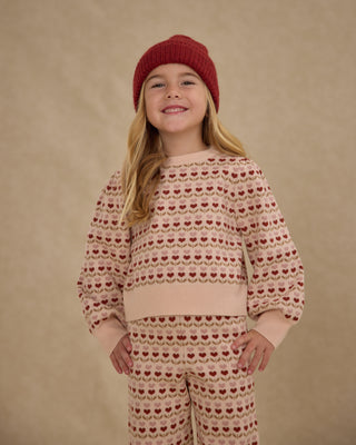 Rylee & Cru Jacquard Knit Set - Ruby Hearts
Child wearing a patterned sweater and pants with a red knit hat against a beige background