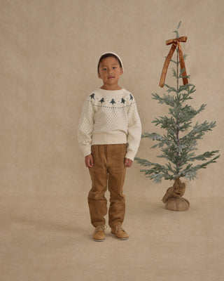 Rylee & Cru Fairisle Sweater - Trees
Child wearing a patterned sweater and brown pants standing next to a small decorated Christmas tree on a beige background