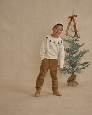 Rylee & Cru Fairisle Sweater - Trees
Child in a white sweater with tree pattern and brown pants standing next to a small decorated Christmas tree on a beige background.