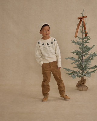 Rylee & Cru Fairisle Sweater - Trees
Child wearing a white sweater with tree patterns and brown pants standing next to a small decorated Christmas tree on a beige background.