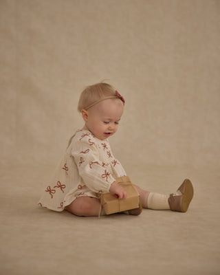 Rylee & Cru Sophia Top + Bloomer Set - Ruby Bows
Baby sitting on a beige background with a cardboard box