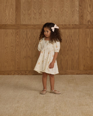 Rylee & Cru Bow Set - Ivory
Rylee & Cru Brea Dress - Nutcracker
Young girl in a floral dress standing against a wooden paneled wall.