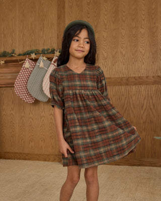 Rylee & Cru Jolene Dress - Holiday Plaid
Young girl wearing a plaid dress standing against a wooden wall.