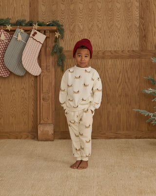 Rylee & Cru Relaxed Sweatshirt & Jogger Sweatpant Set - Christmas Dogs
Child wearing a patterned outfit standing in front of a wooden wall with stockings and Christmas decorations.
