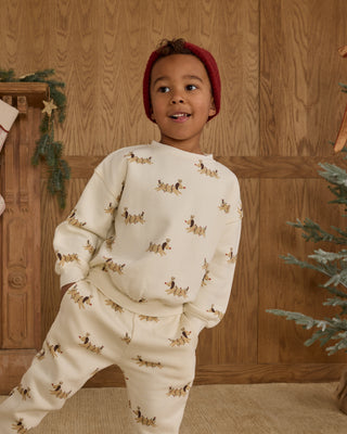 Rylee & Cru Relaxed Sweatshirt & Jogger Sweatpant Set - Christmas Dogs
Child wearing a cream-colored pajama set with dog prints in a festive room.
