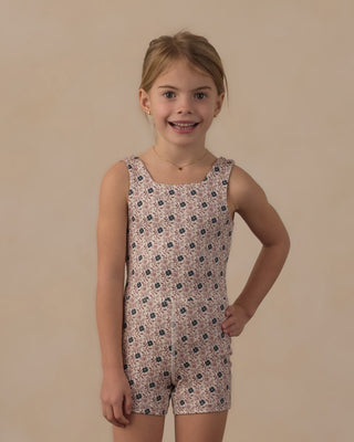 Play by Rylee & Cru Malibu Bodysuit - Blue Primrose
A young girl with blonde hair and a smile on her face, wearing a sleeveless romper with a small floral pattern in pink, beige, and dark blue, standing against a solid beige background.