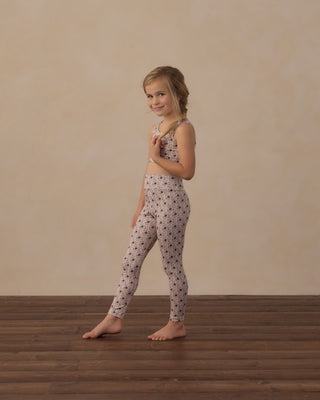 Play by Rylee & Cru Swift Sports Bra - Blue Primrose
Play by Rylee & Cru Basic Legging - Blue Primrose
A young girl stands barefoot on a wooden floor against a beige wall, wearing a matching two-piece lounge set with a small dark floral pattern on a light pinkish-beige background.