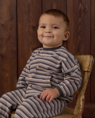 Rylee & Cru Relaxed Set - Blue Stripe
A smiling toddler boy wearing a navy and beige striped long-sleeve pajama set, sitting on a rustic wooden chair against a dark wood-paneled background.