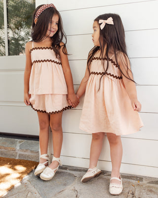 Rylee & Cru Ric Rac Dress - Blush
Two young girls in matching dresses standing against a white wooden wall.