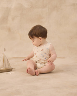 Rylee & Cru Sleeveless One-Piece - Aquatic
Baby sitting on a beige surface with a toy boat, wearing a sleeveless romper with floral patterns.