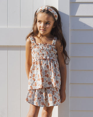 Rylee & Cru Smocked Tank - Americana Floral
Young girl wearing a floral dress standing against a light-colored wall.