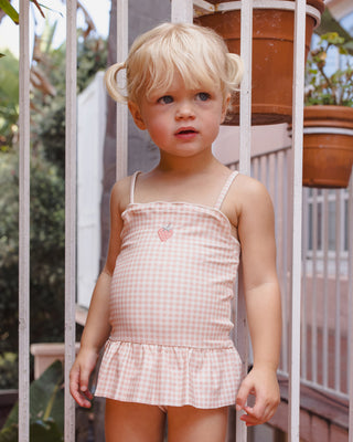 Rylee & Cru Tori Petal Gingham swimsuit for girls, one-piece with skirt detail, displayed in a lifestyle setting.