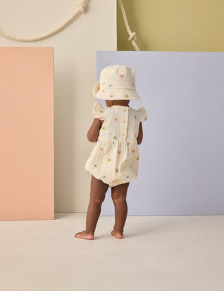 Rylee & Cru Amelia Romper - Embroidered Daisies
Child wearing a floral dress and hat against a colorful background