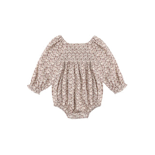 Rylee & Cru Adelaide Romper - Primrose
A baby long-sleeve romper with a dense beige and brown floral pattern, featuring a smocked bodice and ruffled sleeves, shown flat on a white background.