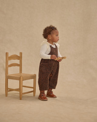 Rylee & Cru Wide Leg Overall - Leopard
Child in brown patterned overalls standing next to a wooden chair on a beige background