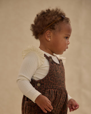 Rylee & Cru Wide Leg Overall - Leopard
Child wearing a leopard print dress with a white shirt underneath on a beige background