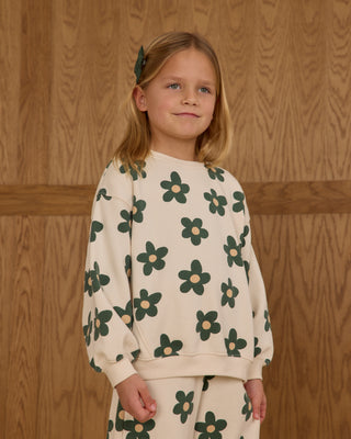 Rylee & Cru Oversized Sweatshirt & Wide Leg Sweatpant Set - Daisy
Young girl wearing a cream sweater with green floral patterns against a wooden paneled wall.