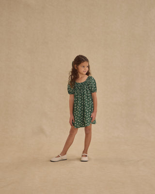 Rylee & Cru Sabrina Mini Dress - Green Ditsy
Young girl wearing a green floral dress against a beige background
