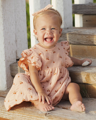 Rylee & Cru Kinsley Dress in melon color, lightweight cotton with a ruffled neckline, styled on a child model outdoors.