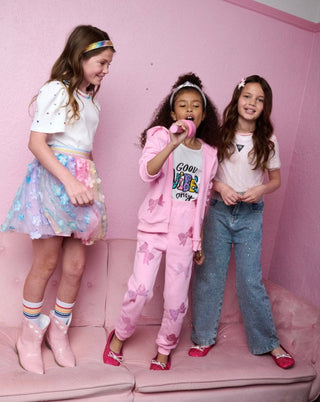 Lola and The Boys Rainbow Sparkle Jeans
Three young girls posing on a pink couch against a pink wall.