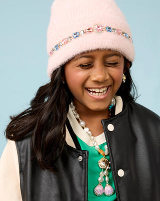 Super Smalls Cotton Candy Jeweled Beanie
Young girl wearing a pink beanie with rhinestone accents, black leather jacket, green shirt, and pearl necklace against a light blue background.