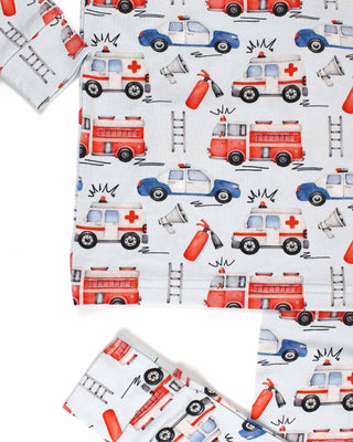 Lev Baby Pajama Set - Ryan
Pattern of fire trucks, ambulances, and police cars on a white background.