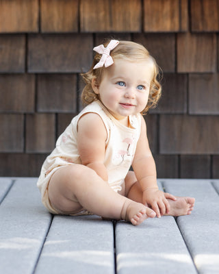 Rylee & Cru Bubble Romper - Flamingo
Baby sitting on a wooden deck with a wooden wall background