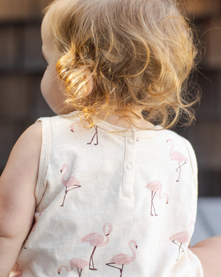 Rylee & Cru Bubble Romper - Flamingo
Child wearing a white sleeveless shirt with pink flamingo patterns, sitting outdoors.