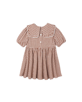 Rylee & Cru Camille Dress - Brick Check
A toddler girl's short-sleeve dress with a brown and white gingham pattern, featuring a large Peter Pan collar with white lace trim, a buttoned front, and a gathered flared skirt.