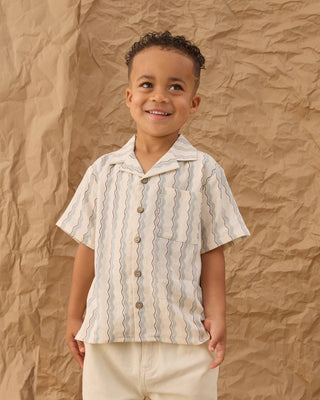 Rylee & Cru Lapel Collar Shirt - Wave Stripe
Child wearing a striped shirt against a textured brown background