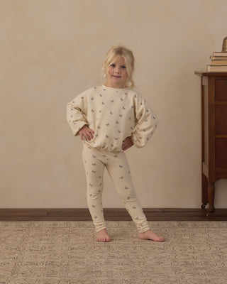 Rylee & Cru Spongy Knit Set - Butterfly Ditsy
A young girl stands barefoot indoors wearing a cream-colored pajama set with a small repeating butterfly print. The set includes a long-sleeve top and matching pants.