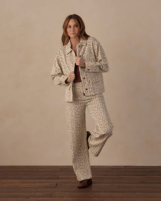 Rylee & Cru Women's Claire Jacket - Leopard
A woman modeling a matching beige and brown animal print pajama set, featuring a long-sleeve button-up shirt and wide-leg pants, paired with a dark red top and brown loafers, against a neutral studio backdrop.