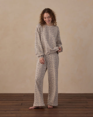 Rylee & Cru Women's Oversized Sweatshirt - Blue Leopard
A woman stands barefoot on a wooden floor against a beige wall, wearing a matching long-sleeve top and wide-leg pants set in a beige and brown animal print.