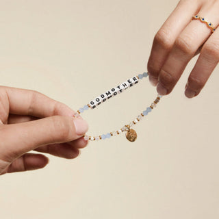 Little Words Project Bracelet - Godmother
Bracelet with 'GODMOTHER' beads held by two hands against a beige background