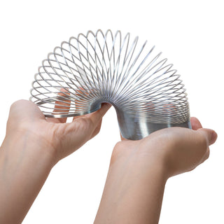 Schylling Sproing Metal Spring Metallic spring toy held between two hands on a white background