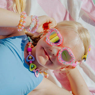 Bling2o Sprinkle Heart Swim Goggles
Child wearing colorful sunglasses and bracelets with a pink background