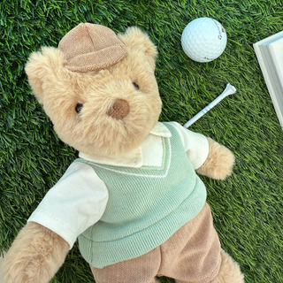 Mon Ami Bogey Golf Bear
Teddy bear in a sweater vest and cap lying on grass with a golf ball and club nearby