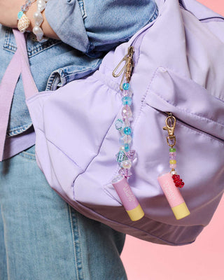 Super Smalls Mermaid Magic Lip Balm Bead Kit
Lavender backpack with colorful lip balm keychains on a pink background
