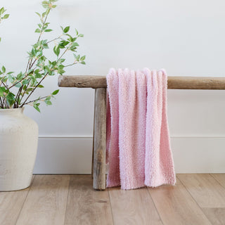 Saranoni Bamboni® Receiving Blanket - Light Pink
Pink textured towel draped over a wooden stool next to a white vase with green branches on a light wood floor.