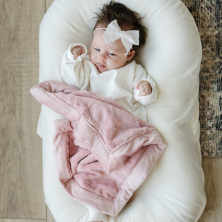 Saranoni Lush Mini Blanket - Ballet Slipper
Newborn baby wrapped in a pink blanket and wearing a white bow, lying on a white cushion.